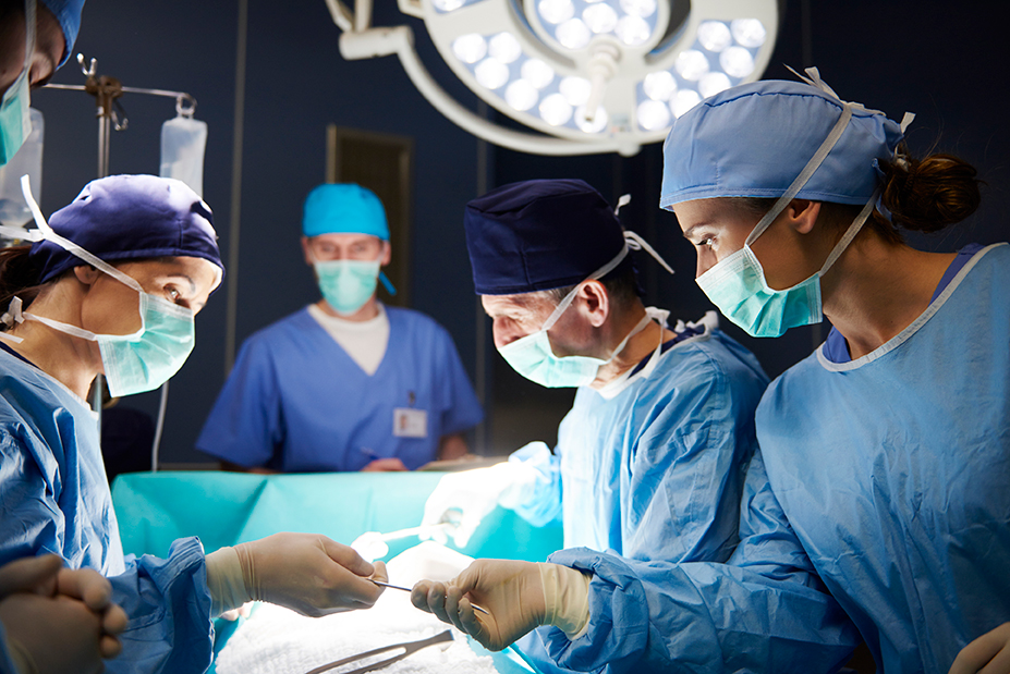 Physicians and assistants perform a surgery.
