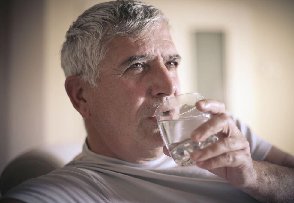an older man drinking water and looking concerned