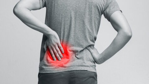 Black and white photo of a person touching a red area on their back indicating kidney pain